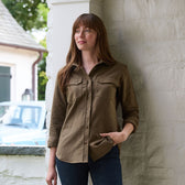 Woman wears the Tom Beckbe Womens Mackay Moleskin Shirt and jeans, standing by a white brick wall, hand in pocket.