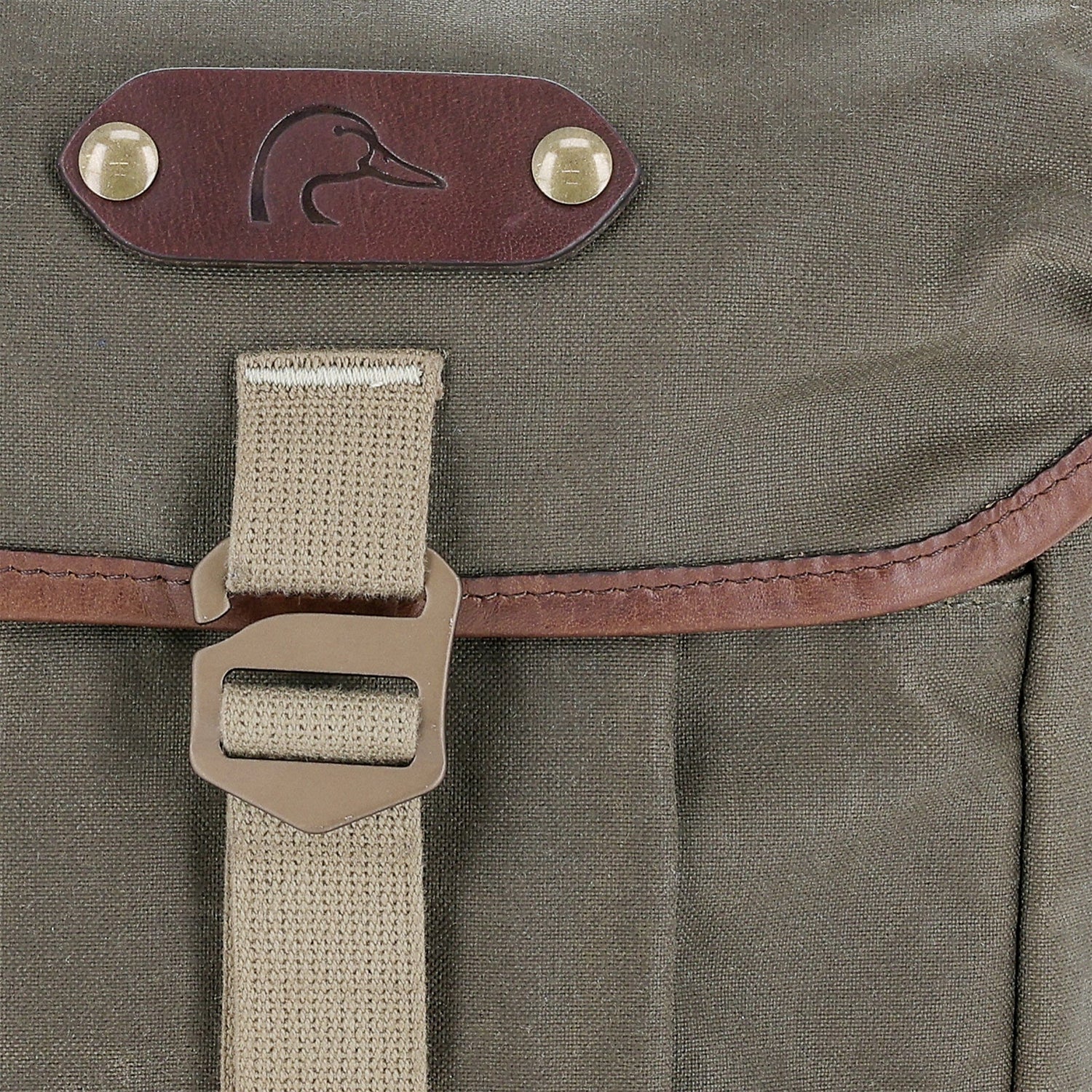 Close-up of a khaki Tom Beckbe DU Timber Bag in waxed canvas with leather trim, metal buckle, and embossed duck logo.