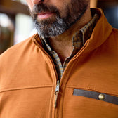 Bearded man wears the Tom Beckbe Tucker Fleece Quarter Zip in orange over a plaid shirt, collar partially unzipped.