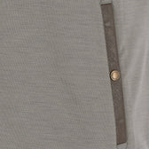 Close-up of a gray fabric garment with a brown vertical trim and a single round metallic button.