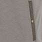 Close-up of a gray fabric garment with a brown vertical trim and a single round metallic button.