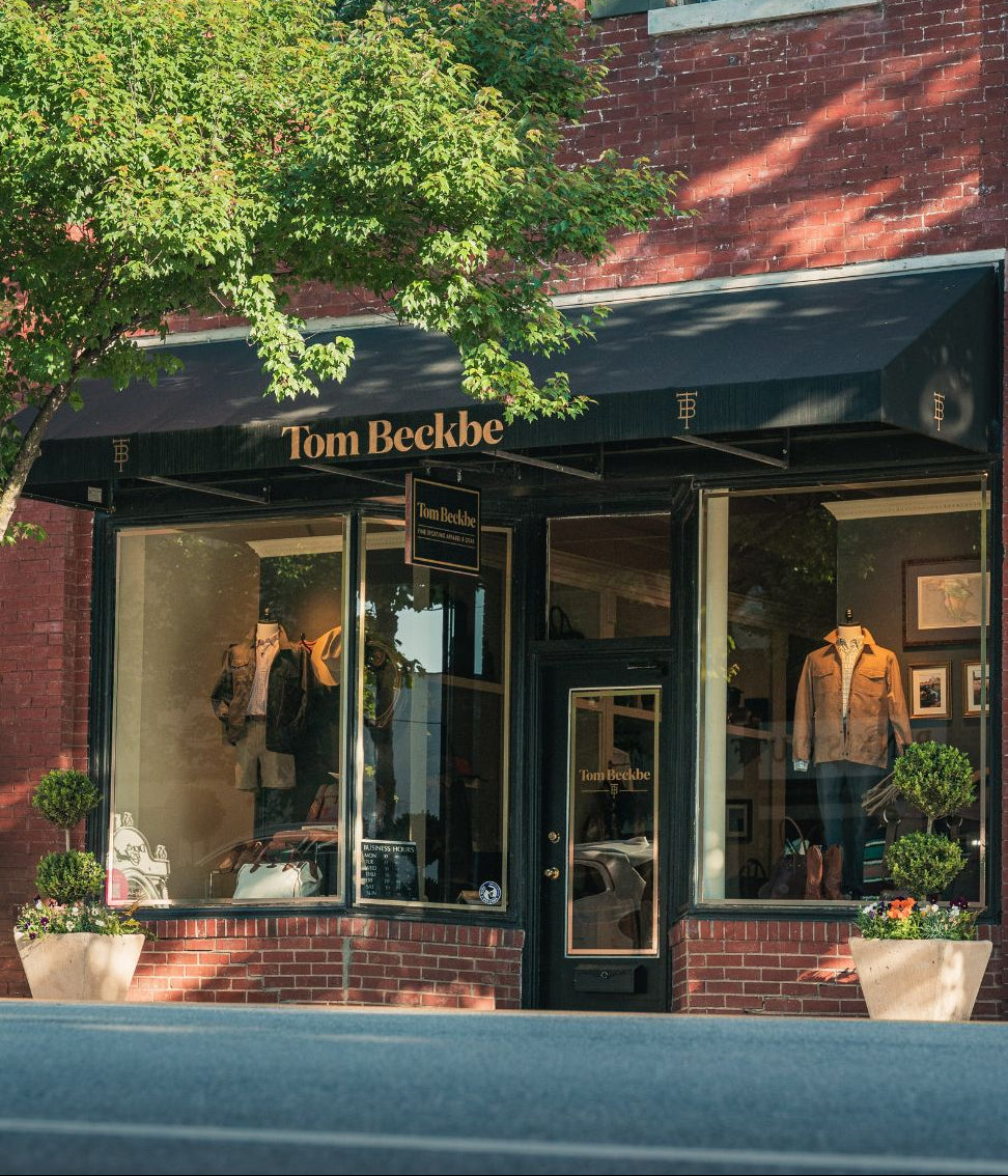 Tom Beckbe store front with glass windows and awning on a brick building