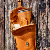 Tom Beckbe Leather Gun Sleeve with a rifle butt visible, resting on a weathered wooden surface.