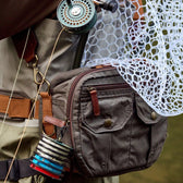 Fly fisherman wearing an all-weather ripstop fishing hip pack, fishing rod, and fishing net.
